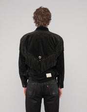 Back view of the black jacket showing the pointed fringed yoke and metal badge.