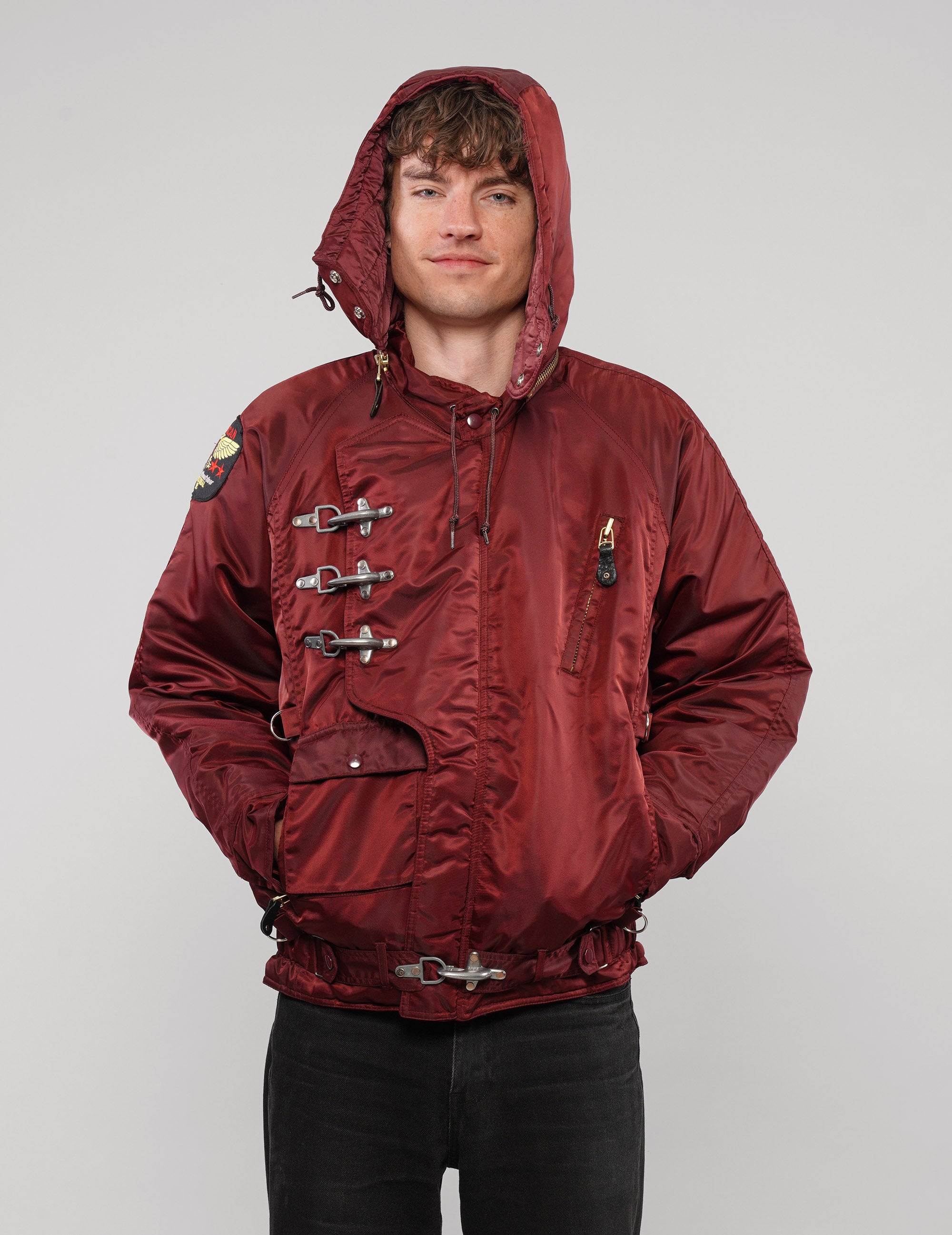 Front view of a burgundy hooded clasp-front jacket with the hood up.