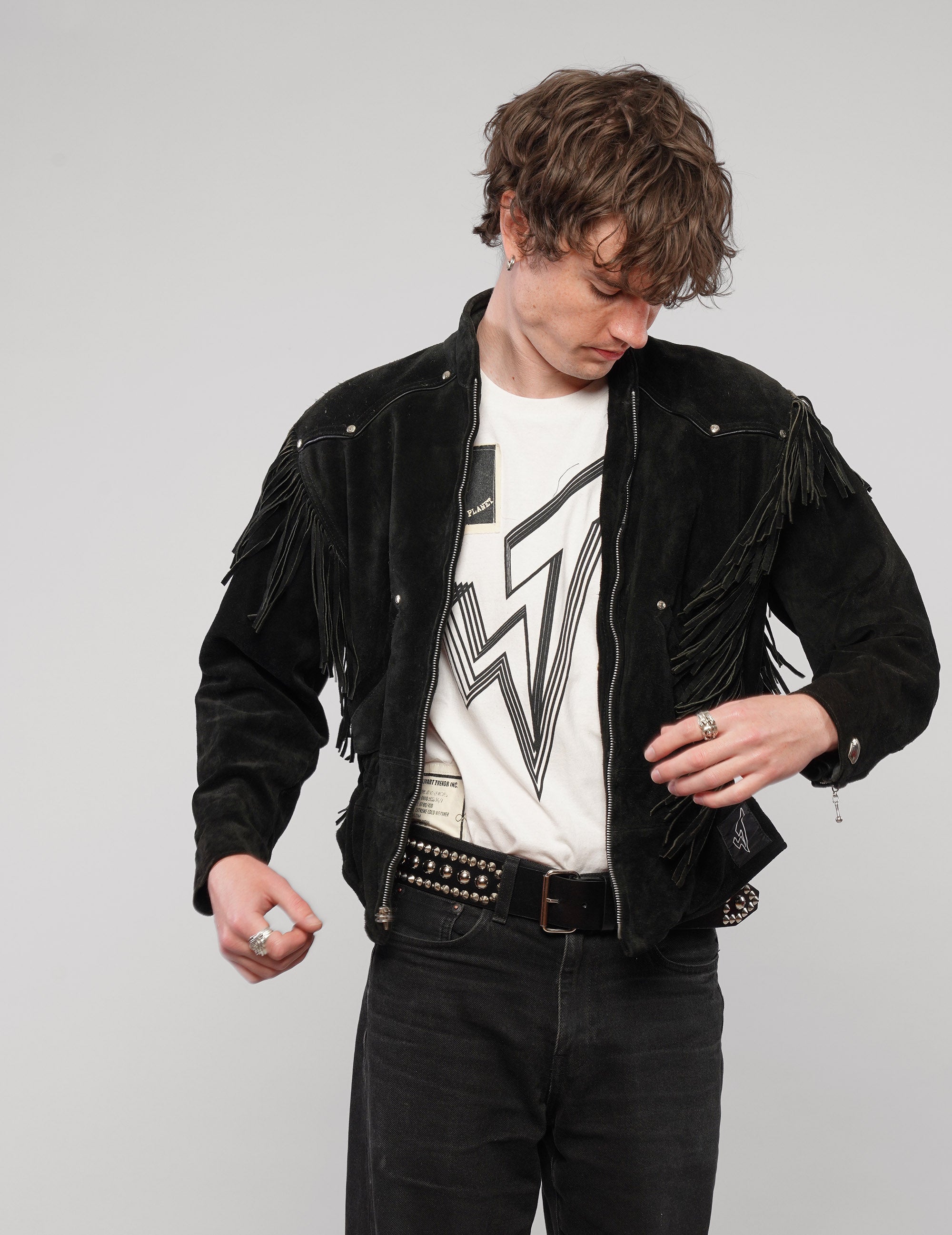 Front view of the black studded fringed jacket worn open over a white T-shirt.
