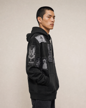 Model turned to the right, showing the side of the patched black hoodie