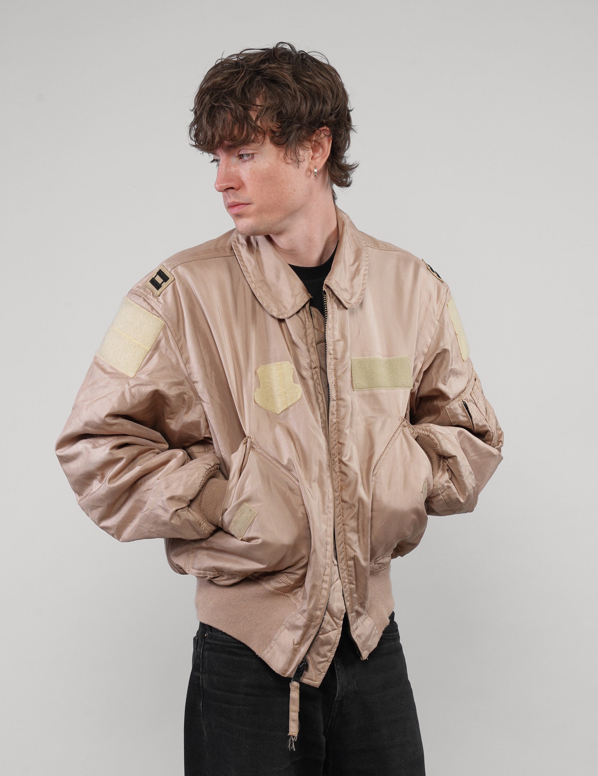 Model wearing one-of-a-kind sand military bomber jacket with pale chest and sleeve patches