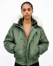 Woman wearing a green N-2B hooded flying jacket, front view, hood down