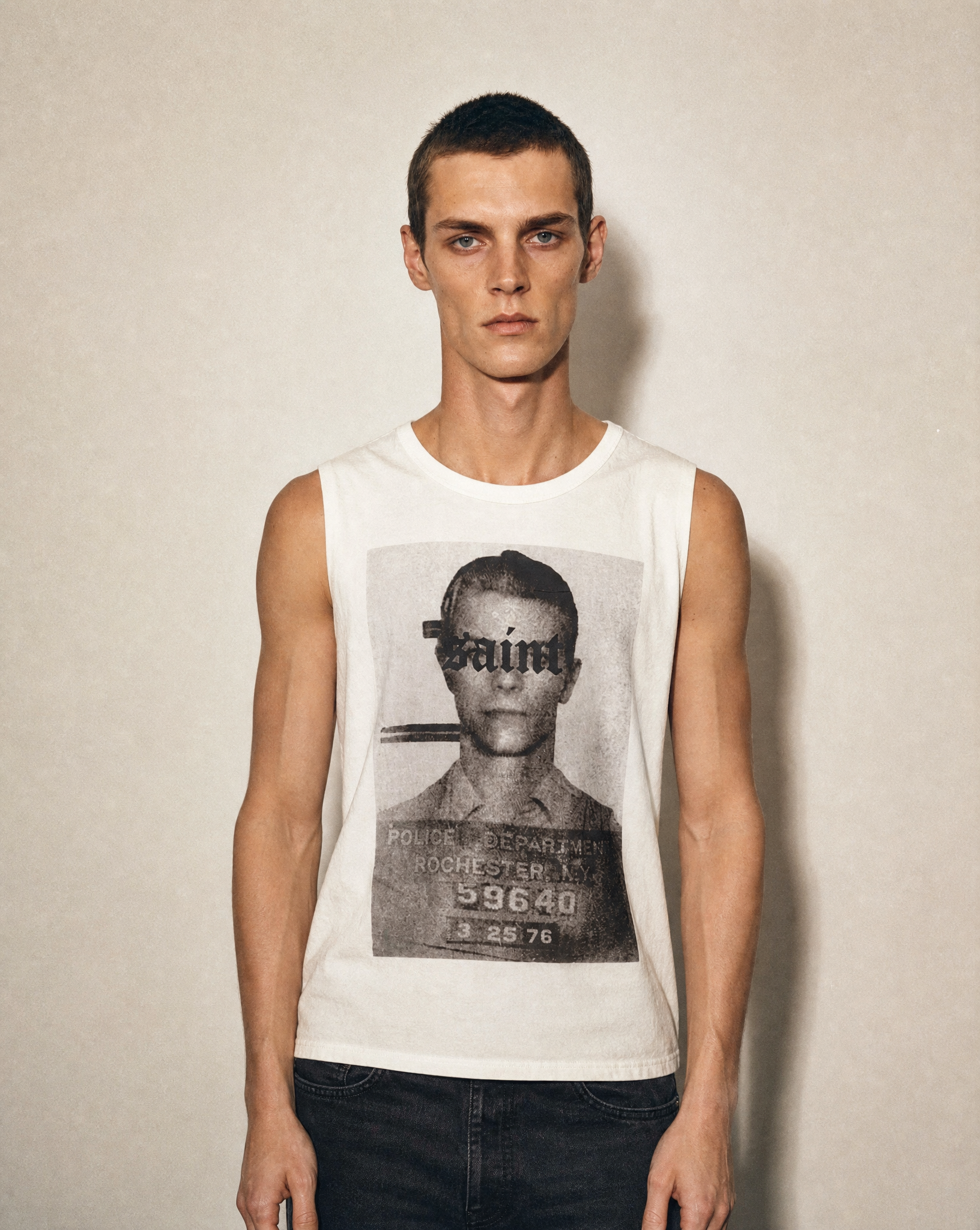 Ecru Saint vest worn front-on, mugshot screen print across the chest