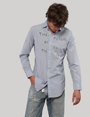 Model looking down while wearing a light blue pinstripe Future Is in the Past shirt with long sleeves.