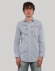 Model wearing a light blue pinstripe Future Is in the Past cotton shirt with black lettering and white buttons.