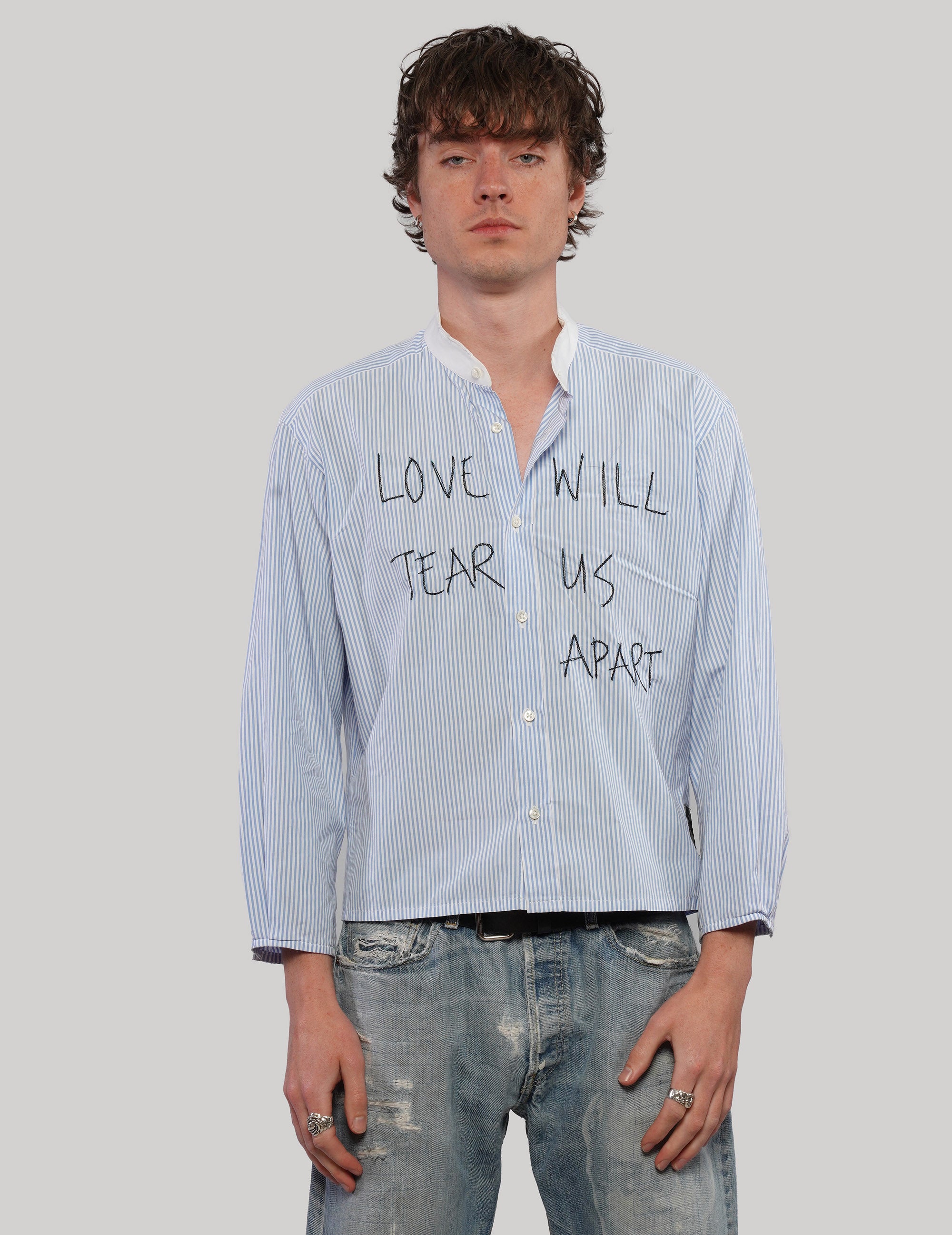 Model wearing a light blue pinstripe Love Will cropped cotton shirt with white collar and black lettering.