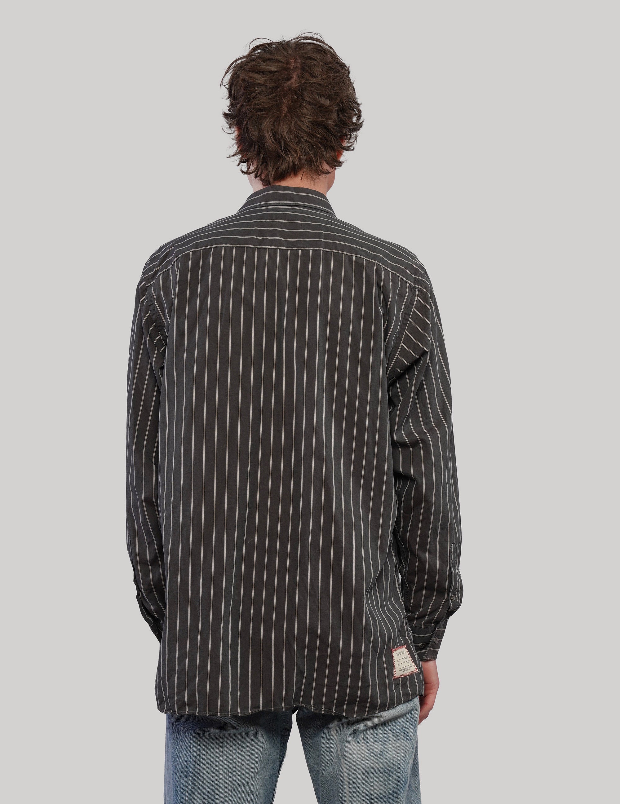 Back view of a black and white vertically striped shirt with long sleeves and a curved hem.