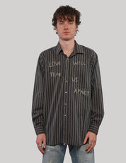 Front view of model wearing a black and white pinstripe 'Love Will' shirt with light graphic lettering and button fastening.