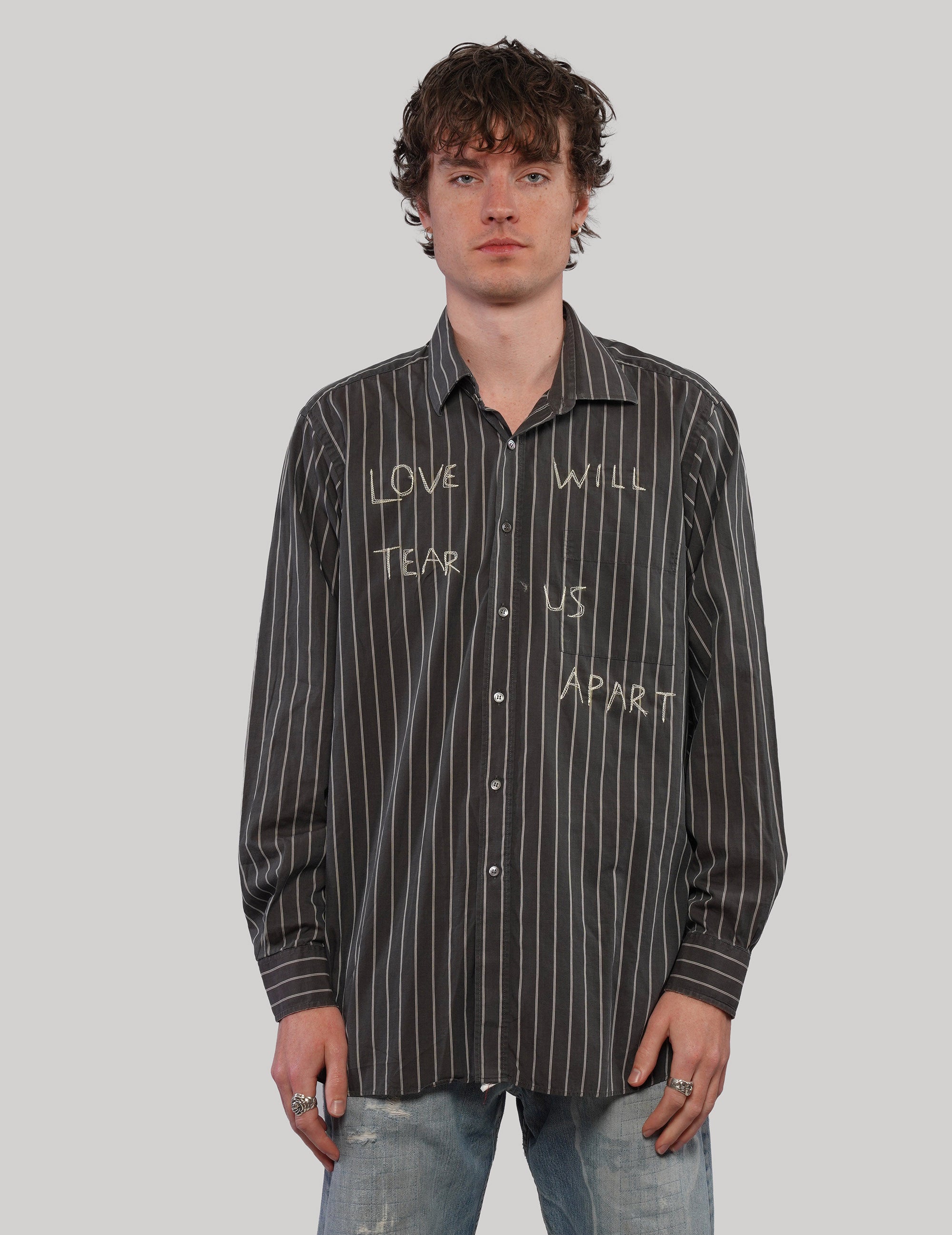 Front view of model wearing a black and white pinstripe 'Love Will' shirt with light graphic lettering and button fastening.