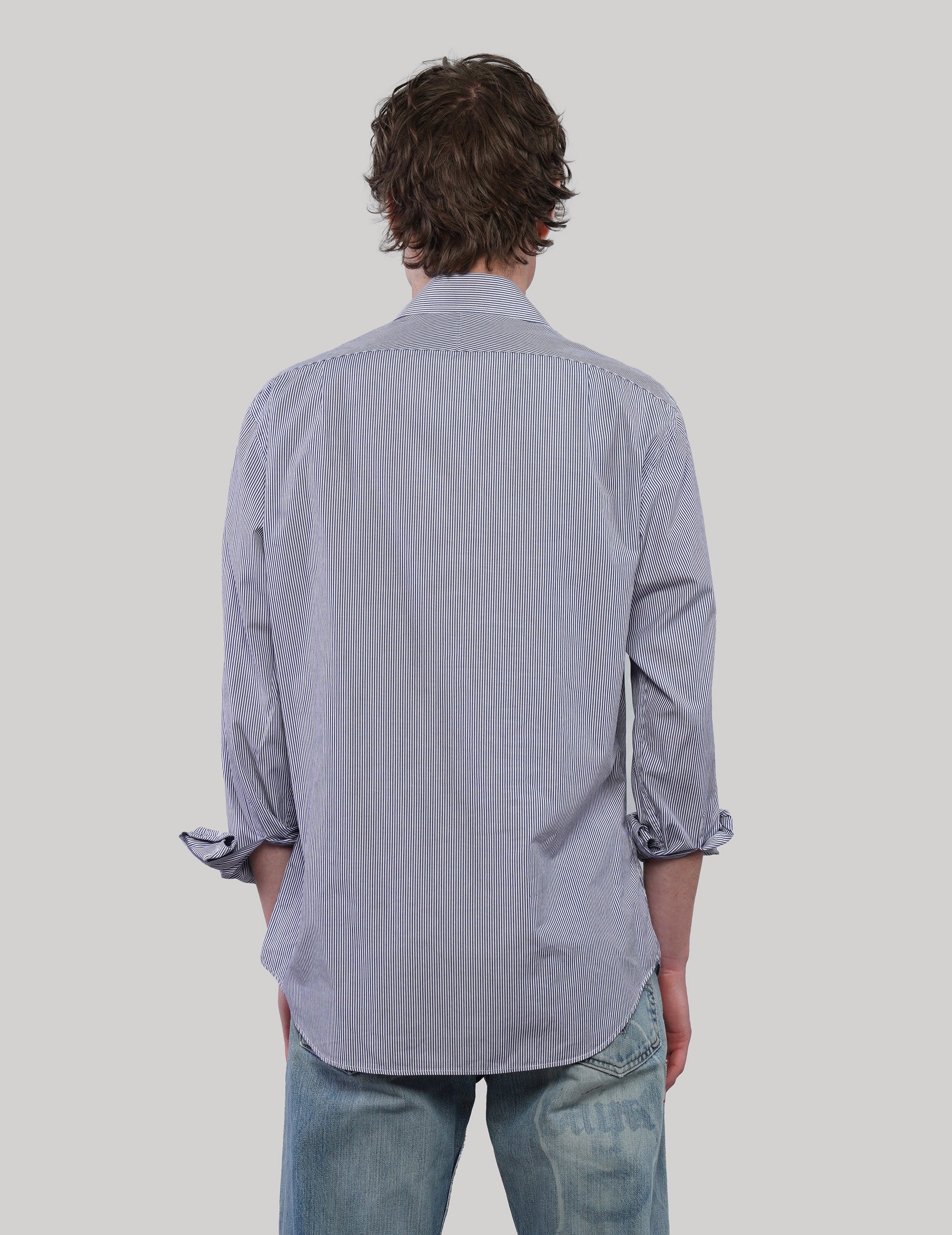 Back view of a blue and white pinstripe cotton shirt showing the relaxed fit, long sleeves and curved hem.