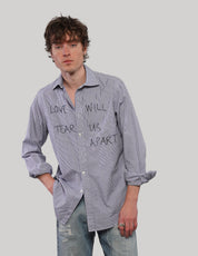 Model wearing an upcycled blue T.M.Lewin pinstripe shirt with black 'Love Will' graphic lettering, styled with faded blue jeans.