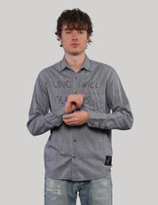 Front view of model wearing a grey 'Love Will' long-sleeve shirt with black graphic lettering, adjusting the shirt cuffs.