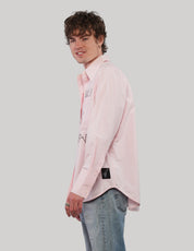Three-quarter side view of model wearing a pink 'Love Will' cotton shirt with pointed collar and relaxed fit.