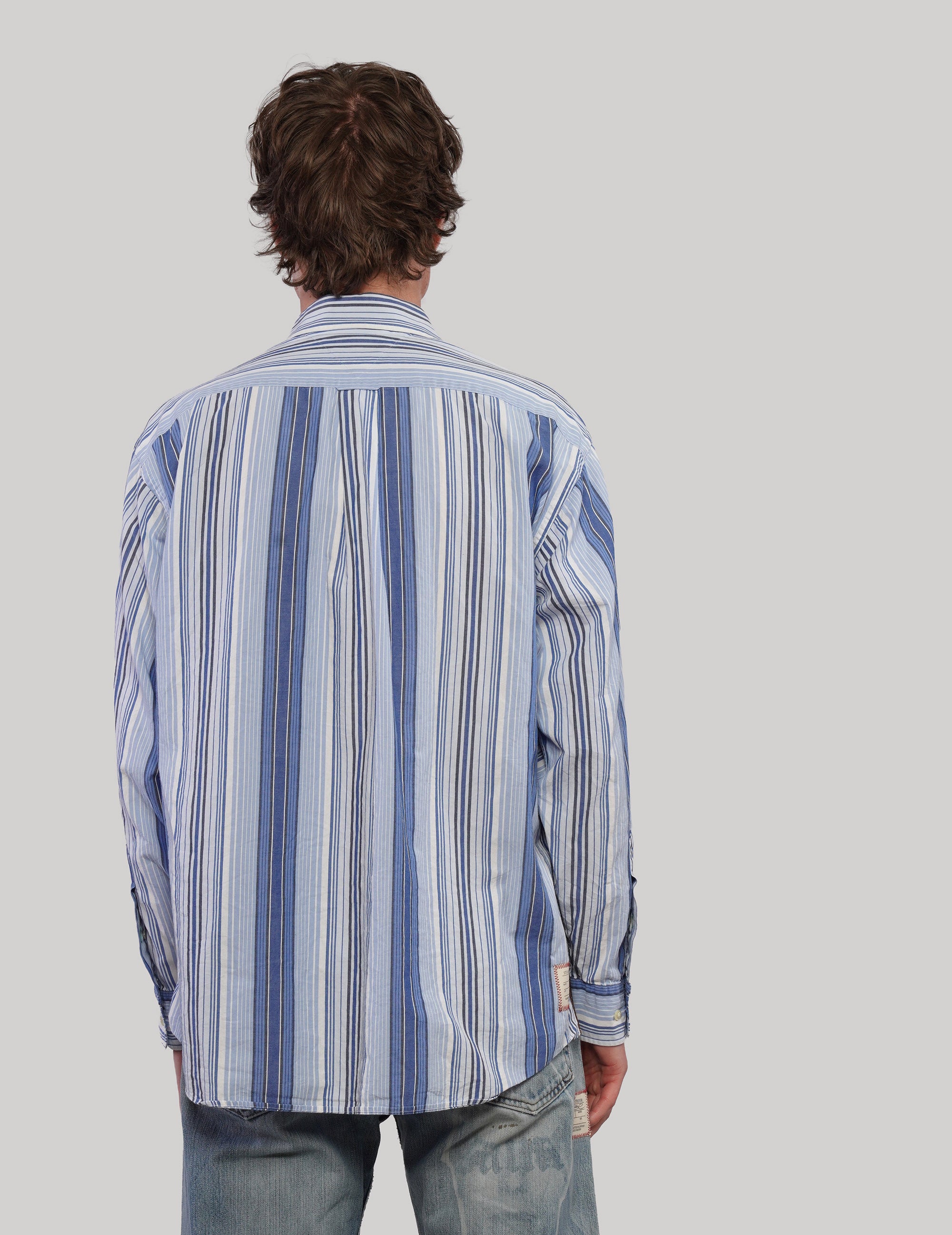 Back view of an upcycled Tommy Hilfiger shirt with blue and white vertical stripes, long sleeves and curved hem.