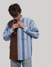 Model looking down while adjusting the collar of a brown and blue striped upcycled vintage shirt.