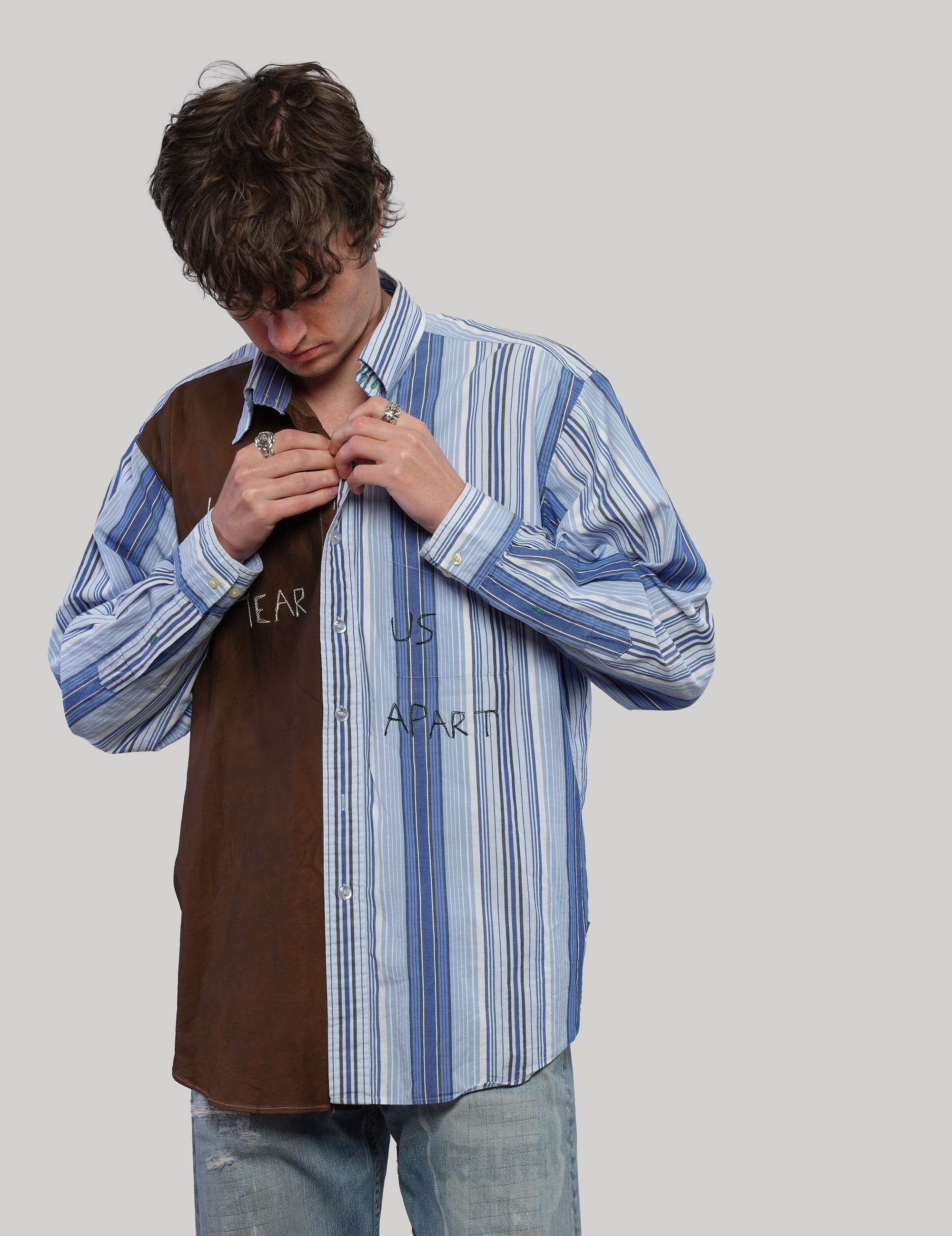 Model looking down while adjusting the collar of a brown and blue striped upcycled vintage shirt.
