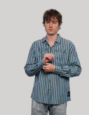 Model adjusting the cuff of a teal and light blue striped 'Love Will' shirt with long sleeves and button fastening.