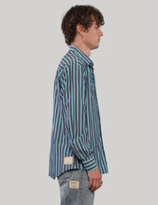 Side view of a teal and light blue vertically striped shirt showing the pointed collar, long sleeves and loose silhouette.