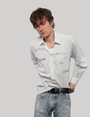 Model wearing a white 'Love Will' striped shirt with black lettering, tucked into distressed blue jeans.