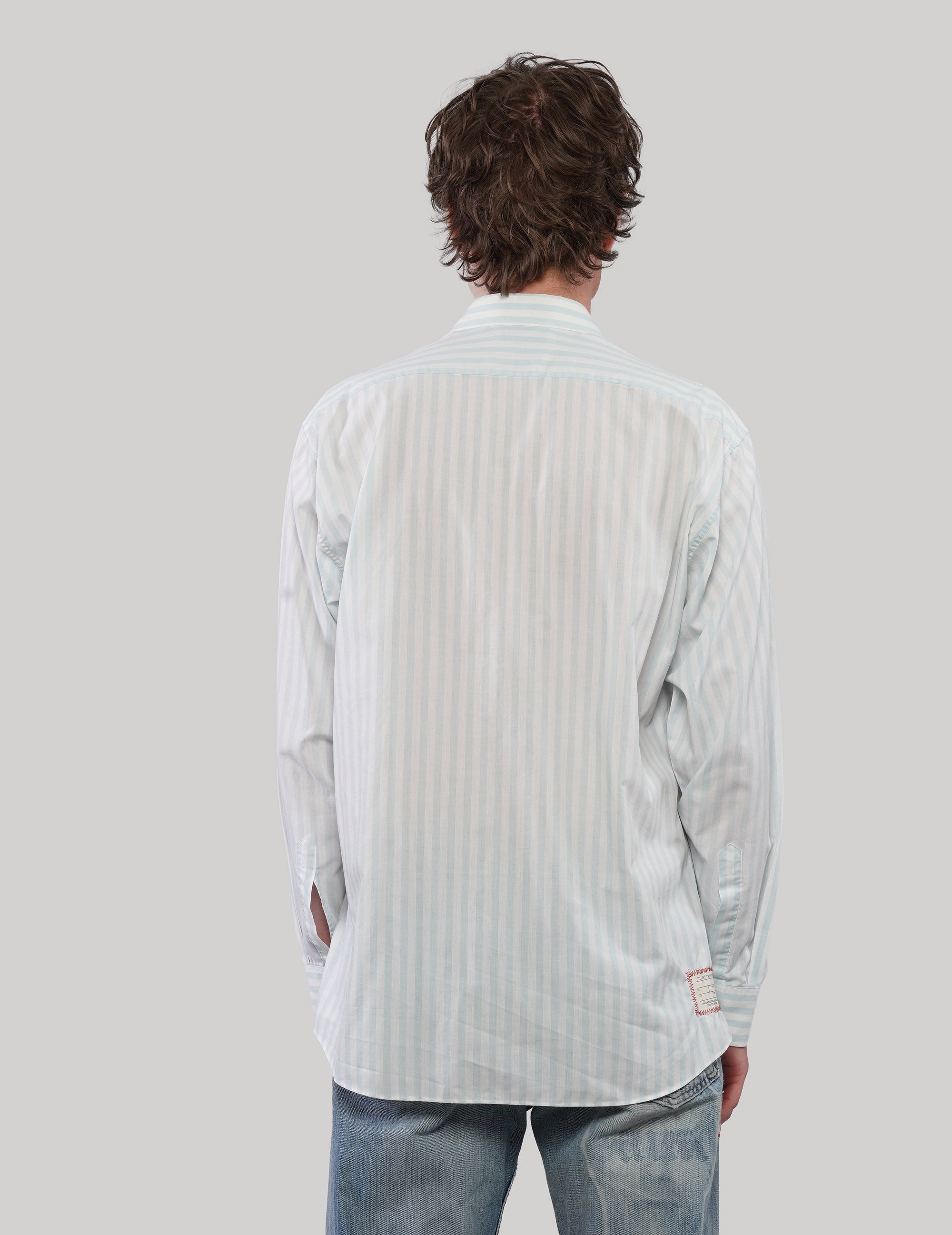 Back view of a white pinstripe shirt showing fine vertical stripes, long sleeves and a curved hem.