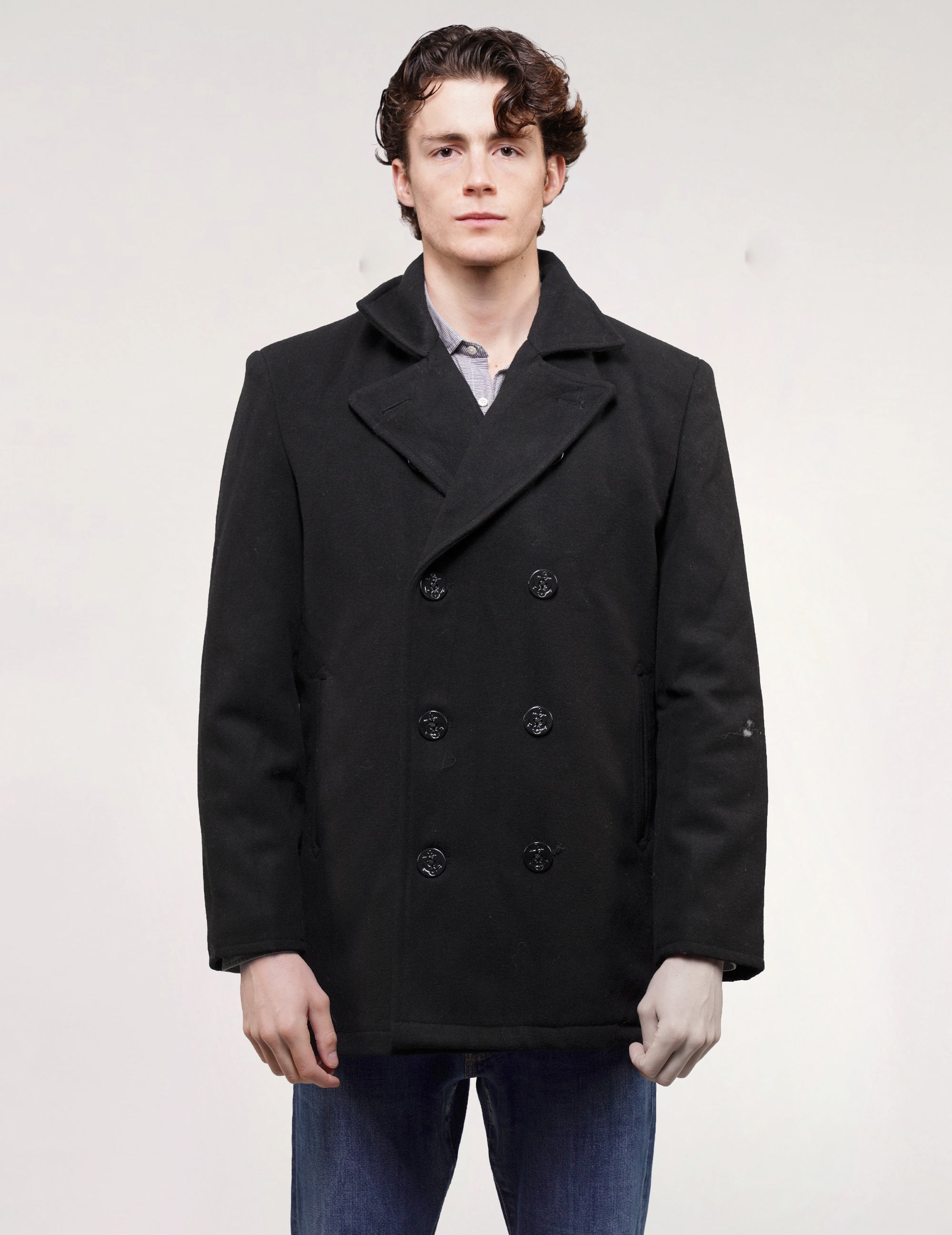 Full front view of black double-breasted naval peacoat with wide lapels, worn with blue jeans.