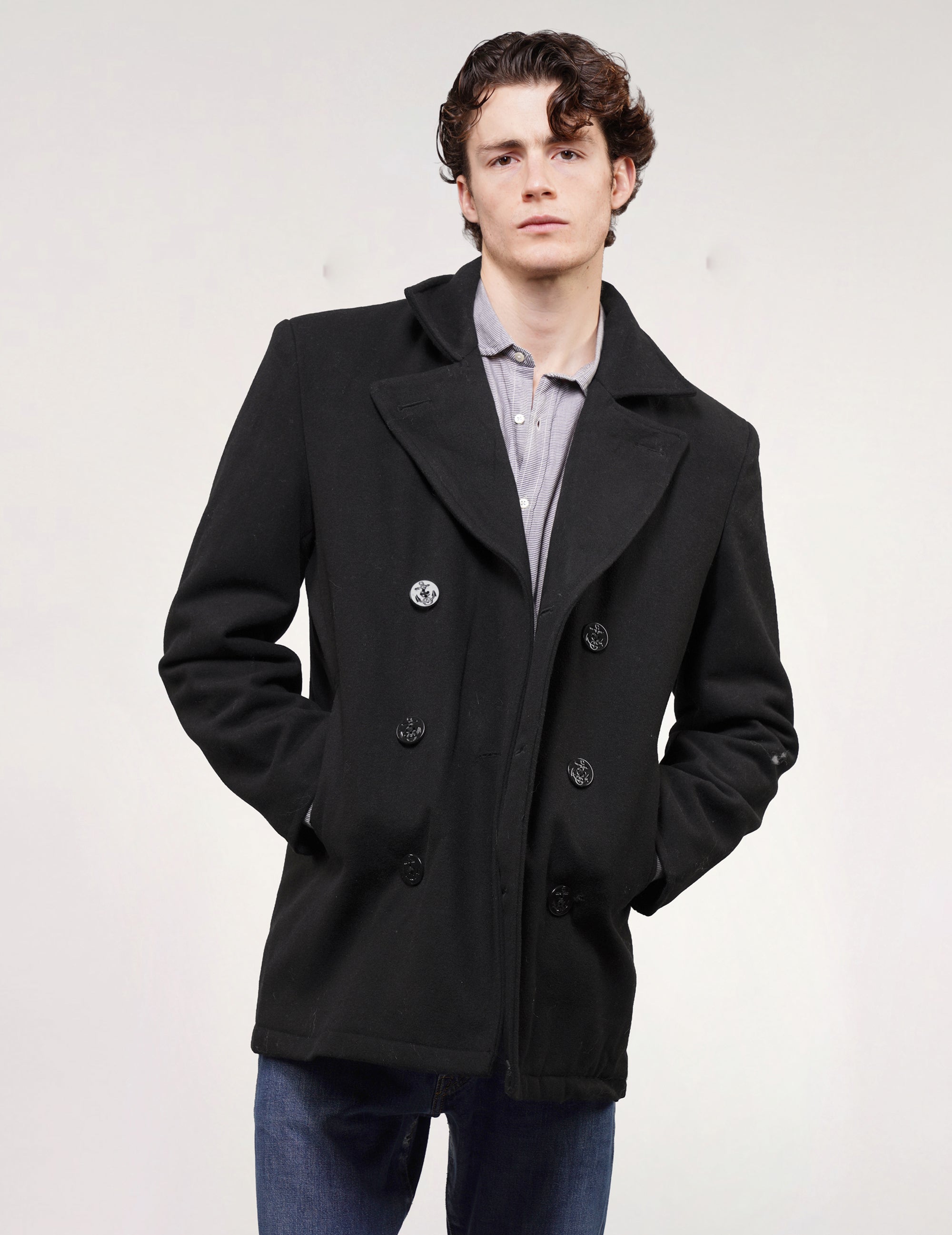 Full front view of black double-breasted naval peacoat with wide lapels, worn with blue jeans.